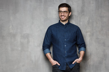 European man in denim shirt with hands in pockets looking aside, copyspace on left