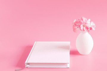 Elegant floral soft composition with diary. Flowers in vase, notebook  on pastel pinkbackground. copy space