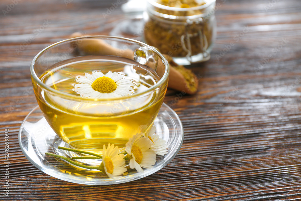 Wall mural cup of hot chamomile tea on wooden table