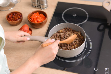 Woman cooking traditional chili con carne in kitchen