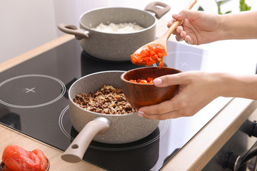 Woman cooking traditional chili con carne in kitchen