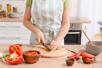Obraz na płótnie Canvas Woman cutting fresh herbs in kitchen
