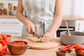 Woman cutting fresh herbs in kitchen