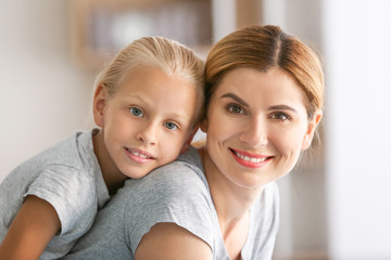 Portrait of mother with cute little daughter at home