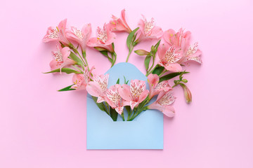 Envelope with beautiful flowers on color background