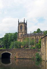 Fototapeta na wymiar a stone bridge crossing the canal in sowerby bridge west yorkshire with the historic christ church building surrounded by trees