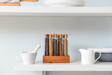 Assortment of spices in tubes on shelf in kitchen