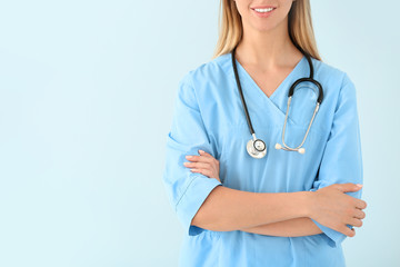 Female nurse with stethoscope on color background