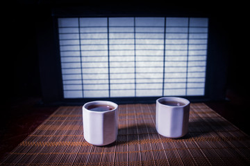 Tea concept. Japanese tea ceremony culture east beverage. Teapot and cups on table with bamboo leaves on sunset