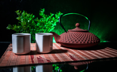 Tea concept. Japanese tea ceremony culture east beverage. Teapot and cups on table with bamboo leaves on sunset