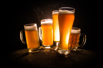 Creative concept. Beer glasses on wooden table at dark toned foggy background.