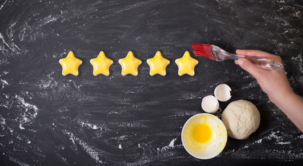 five star customer rating survey. Woman is painting her stars from dough with eggs on yellow