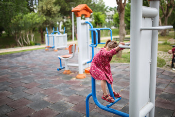 Fototapeta premium Caucasian girl child plays on street gym equipment