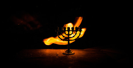 Fototapeta na wymiar Low key image of jewish holiday Hanukkah background with menorah on dark toned foggy background