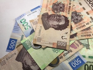 Mexican peso bills spread over white background