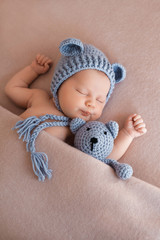 Cute newborn baby girl sleeping with a teddy bear.