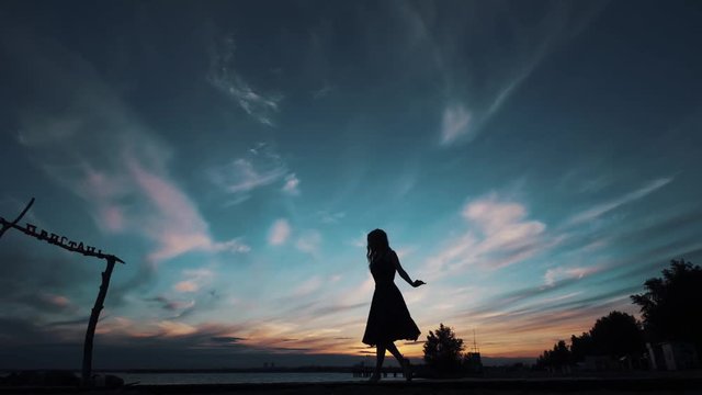 silhouette of a ballerina dancing against the sunset sky. girl dancing and spinning on tiptoe.