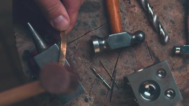 Master goldsmith working with gold-shaping of the object by hammering