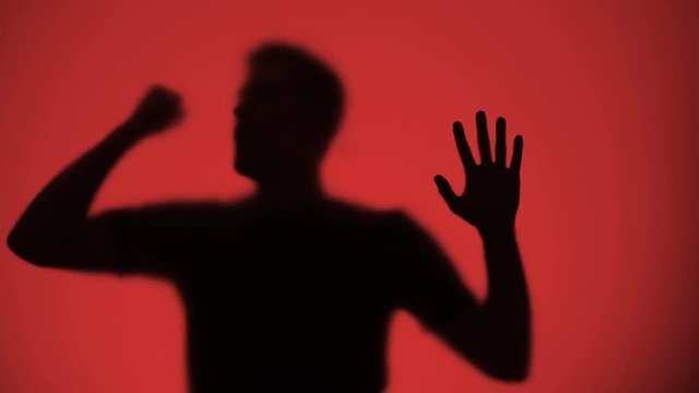 Male silhouette knocking on glass, red lights blinking on background, warfare