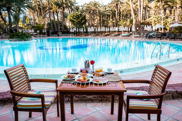 breakfast by swimming pool, fruit bread and coffee with orange juice by the pool at an luxury vacation