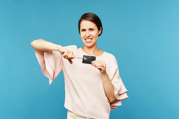 Young elegant customer cutting invalid black credit card with scissors after end of expiration date