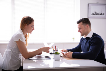 Interviewer Looking At Document Of Female Candidate