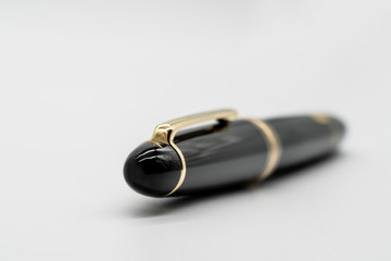 Black and gold fountain pen isolated on white background with shallow depth of filed.