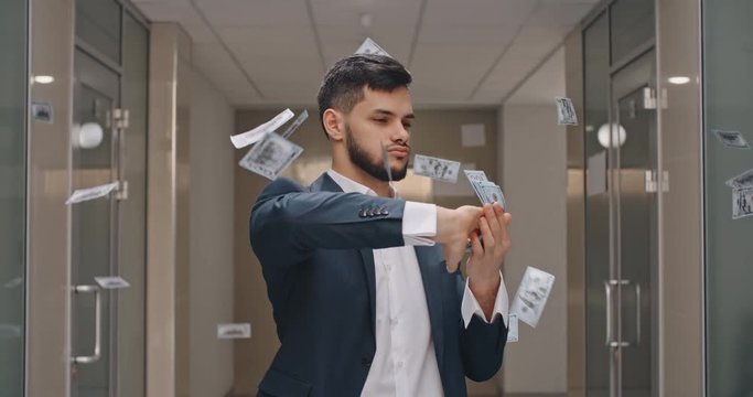 Caucasian man with arrogant face is standing in office hall throwing money in air, celebrating his success - way to success concept 4k