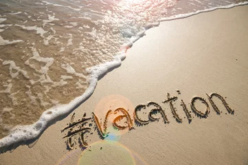 Foto op Plexiglas Modern travel message for the beach with a social media-friendly hashtag written with the word "vacation" in smooth sand with incoming wave © lazyllama
