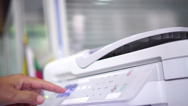 Documents printing concept : Business man hand pressing button machine supplies in control panel laser printer for copy scanner and printing document report graph chart in busy office 