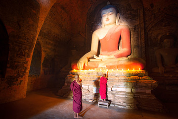 Monk in Bagan old town pray a buddha statue with candle