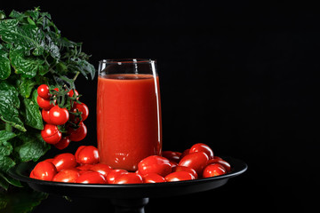 glass of tomato juice covered with cherry tomatoes comes from a natural tomato bush, conceptual image.