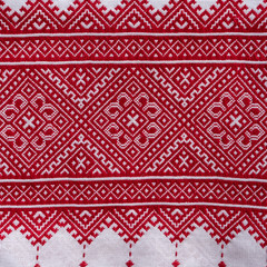 Detail of embroidered ornament with red threads on white fabric, ukrainian folk embroidery, close up