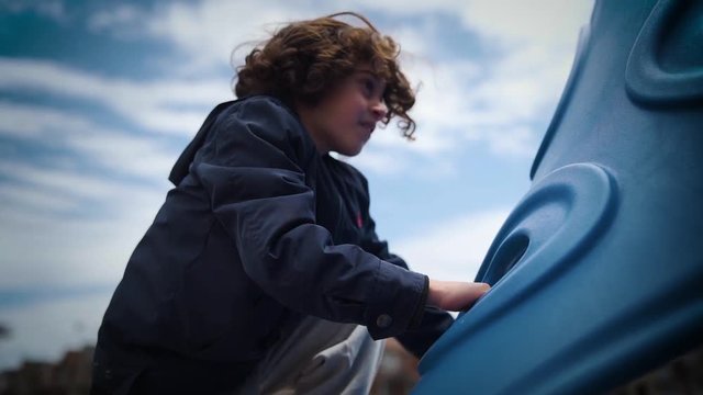 Cute boy climbing up a playground outside.