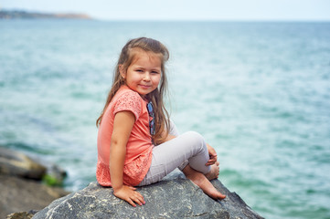 Beautiful little girl on the sea coast . Children's summer holidays