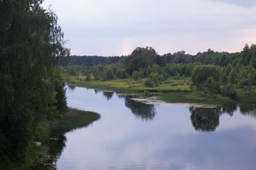 summer sunset in the village by the river in the forest