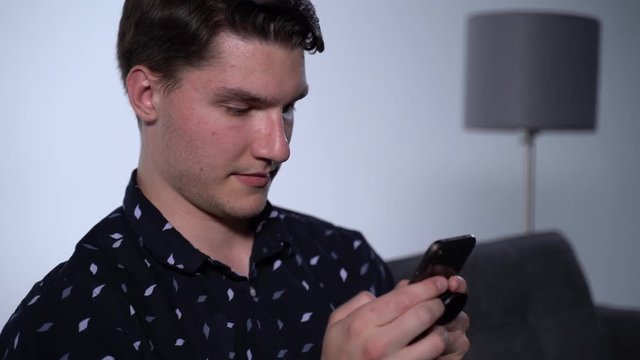 Pan Right of Caucasian Man on Phone on Couch with Blank Expression