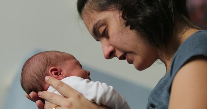 Mother and newborn baby interaction mom kissing infant during first day of life showing love and affection