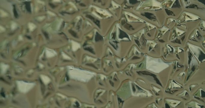 4k cadre of different forms on plexiglas reflecting light. camera tilting up.