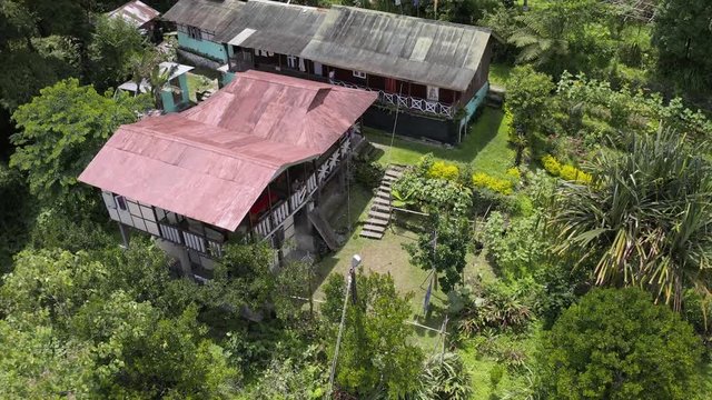 Aerial, reverse, drone shot, away from a detached house, a yard and garden, in the middle of Indian forest, on a sunny day, in Sikkim, India