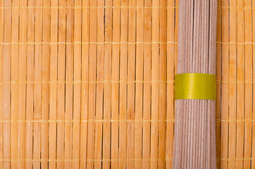 Dry brown noodles on wooden background.