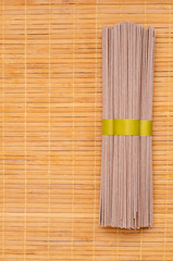 Dry brown noodles on wooden background.
