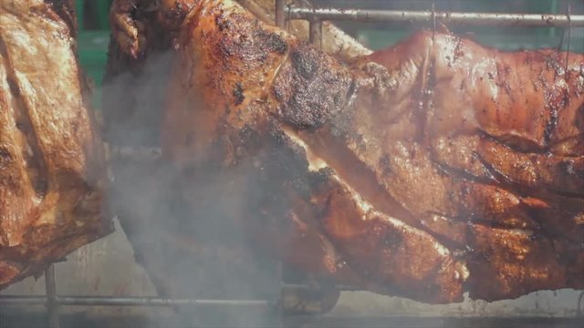 Great close-up slow-motion shot of some delicious looking suckling pig and some ribs rotating on a grill. Viola E Petisco - Brazil