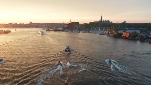 Jet ski team following boat up river during golden hour sunset towards waterfront properties