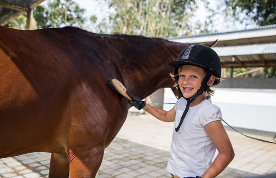 Young girl taking care of her horse at the farm