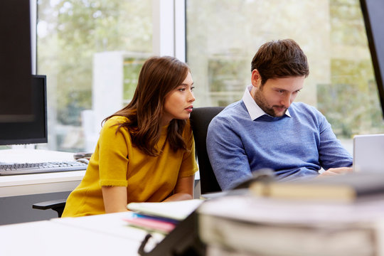 Colleagues Looking At Digital Tablet In Office