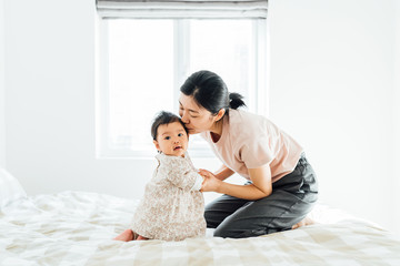 Adorable baby girl and her mother playing at home