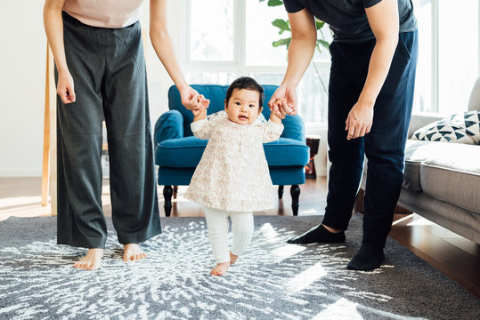 Adorable girl learning walk with her parents help