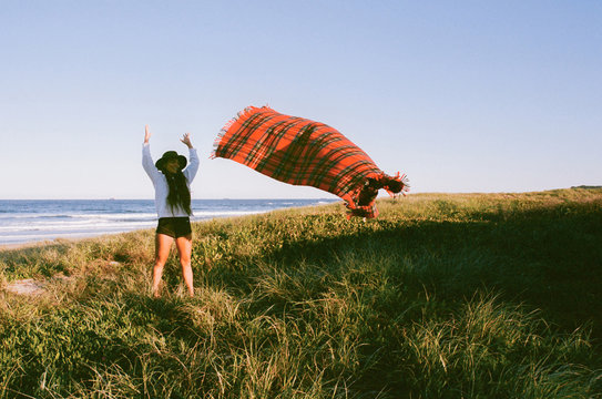 Tanned woman throwing rug in air