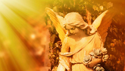Antique statue of wonderful angel in the rays of the sunl on sky background